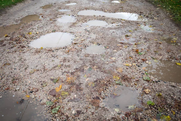 Wet gravel road. Autumn day, weather and season. Wood leaves and mud — Stock Photo, Image