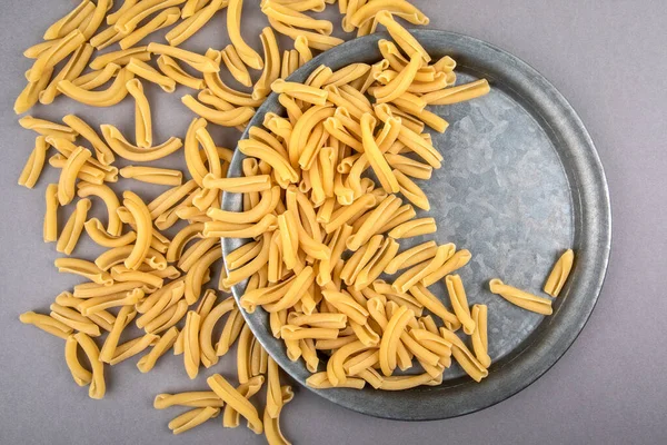 Strozzapreti, pasta italiana in piatto di metallo su un tavolo grigio — Foto Stock