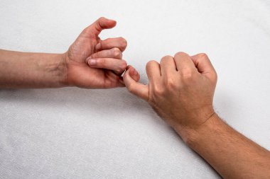 Mutlu çift el ele tutuşuyor. Aşkı, ilişkileri, birliği ve aileyi simgeler. Beyaz bez ve yatak.