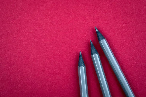 Lápis cinzentos num fundo vermelho. Espaço de texto livre para publicidade e marketing — Fotografia de Stock