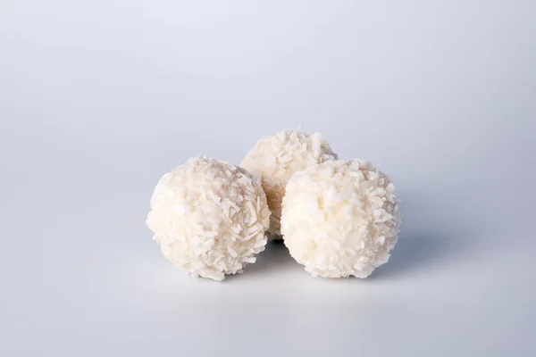 Three white candies with coconut chips, on a white background. Sweets, holidays and anniversaries — Stock Photo, Image