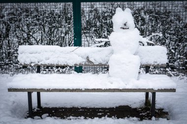 Bankta kardan adam. Kış eğlencesi. Soyut yalnızlık kavramı, anonimlik.
