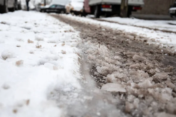 Estradas nevadas e difíceis após a queda de neve no inverno. Neve lamacenta, carros embaçados no fundo — Fotografia de Stock
