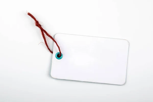 Bílá cenovka s červenou šňůrou na bílém pozadí — Stock fotografie