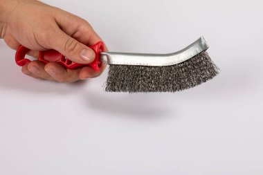 Bir adamın elinde kırmızı plastik saplı metal tel fırça. Beyaz arkaplan