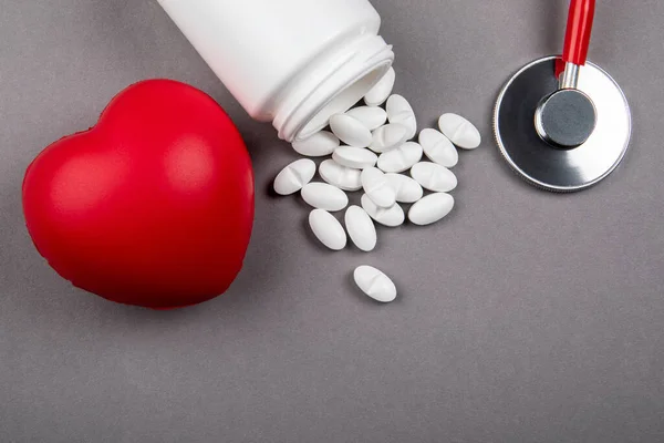 白色药物，红色橡胶心脏，灰色背景听诊器 — 图库照片