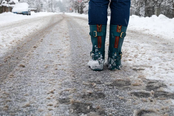 Woman in rubber boots on a snowy and slippery road. Weather and movement — Stock Photo, Image