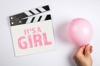 O bir kız. Doğum günü ve sonografik inceleme konsepti. Sinema alkışları ve beyaz arka planda pembe bir balon.