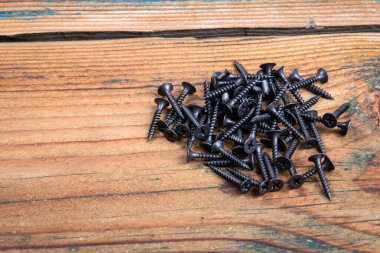 Ahşap bir arka planda siyah vidalar. Sıva tahtası vidaları