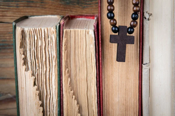 Old books and wooden cross. Religion, prejudice, prohibition and faith concept — Stock Photo, Image