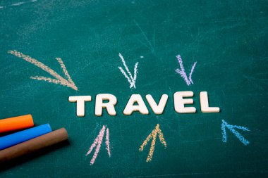 Seyahat et. Tahta alfabenin beyaz harfleri. Yeşil tebeşir tahtasında renkli tebeşir parçaları