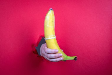 Taze sarı muzlu prezervatif. Kırmızı kağıt arkaplan