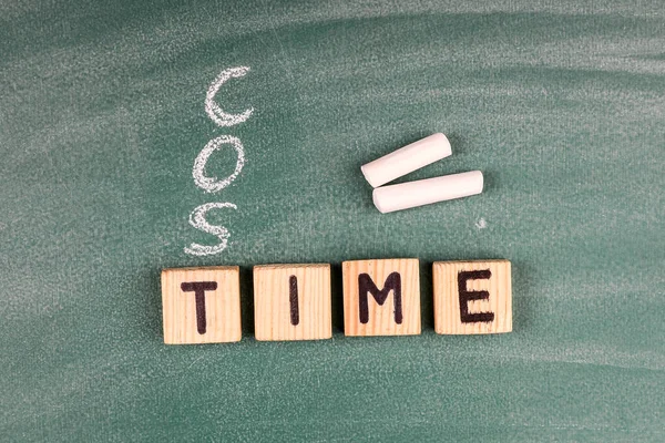 Time an Cost concept. Wooden alphabet letters on a green chalk board