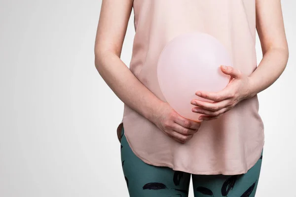 Woman pregnant or bloated belly. Pink balloon in womans hands. Abstract background — Photo