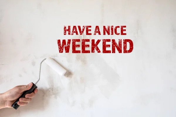 Haben Sie ein schönes Wochenende. Farbwalze in der Hand eines Mannes. Hintergrund Betonmauer — Stockfoto