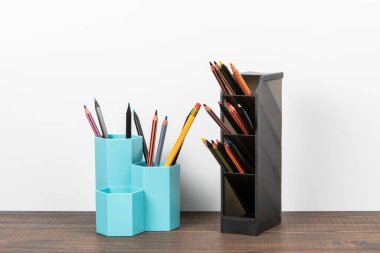 Renkli kalemli tutucu. Ofis ve öğretmenlik malzemeleri. Tahta masa ve beyaz arkaplan