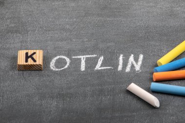 Kotlin kodu ve programlama dili kavramı. Siyah tebeşir tahtasında renkli tebeşir parçaları
