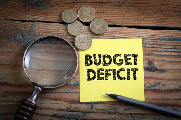Budget Deficit. Euro cash and magnifying glass on a wooden background — Stock Photo, Image