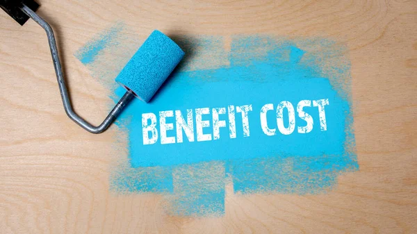 Benefit Cost. Paint roller with blue paint on a wooden surface