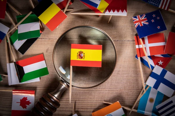 Spanish Flag and magnifying glass. Flags of different countries on a wooden background