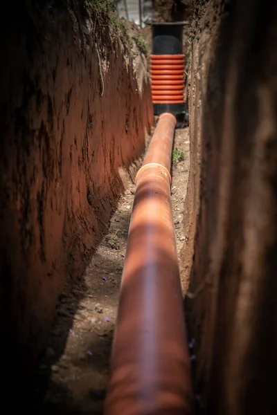 Tuyau de vidange en plastique orange. Fosse creusée, journée ensoleillée — Photo