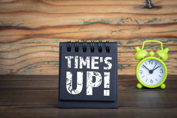 Times Up. Caderno preto e despertador verde em um fundo de madeira — Fotografia de Stock