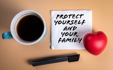 Kendini ve aileni koru. Kahve fincanı ve peçete masanın üstünde.