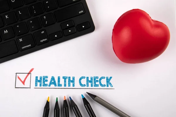 Controllo dello stato di salute. Cuore in gomma rossa e tastiera nera su sfondo bianco — Foto Stock