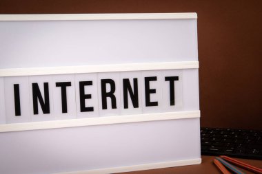 Internet. Light box with text and computer keyboard on a brown background