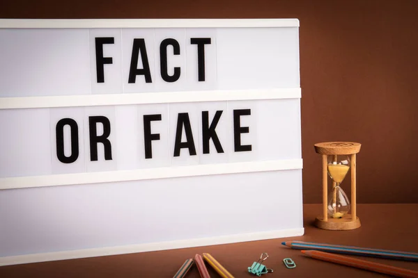 Falsk eller falsk. Hvit lysboks med tekst på brun bakgrunn – stockfoto