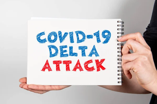 COVID-19 DELTA ATTACK. Caderno com informação em uma mão de mulher — Fotografia de Stock