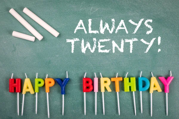 Siempre veinte. Velas de aniversario en una pizarra verde — Foto de Stock