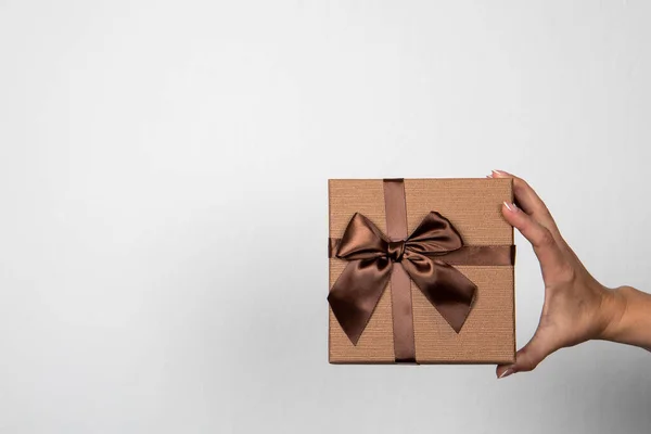 Hnědá dárková krabice v ženské ruce na světlém pozadí — Stock fotografie