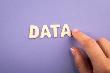 Veri kavramı. Ahşap harfler ve mor arka planda bir kadın eli.