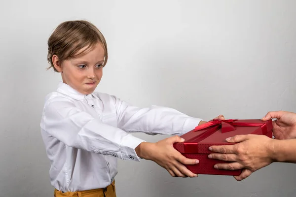 Pojken tar en födelsedagspresent eller julklapp. Stor röd låda — Stockfoto