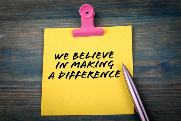 We geloven in het verschil maken. Gele plakkerige noot op tafel — Stockfoto