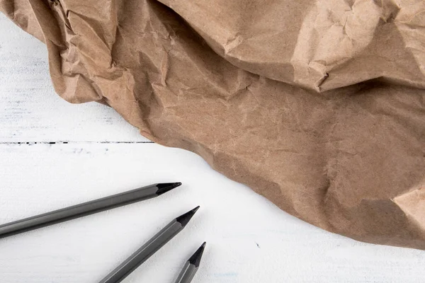 Zerknülltes Packpapier und Bleistifte auf dem Tisch — Stockfoto