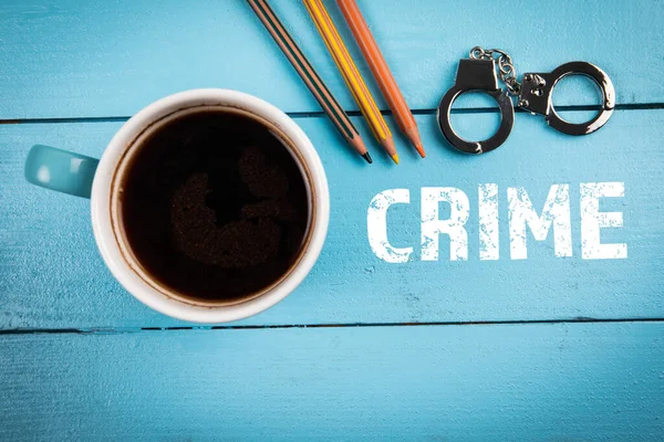 CRIME, juridik, utredning och domstolsbegrepp. Kaffemuggar och handbojor i miniatyr på ett träbord — Stockfoto