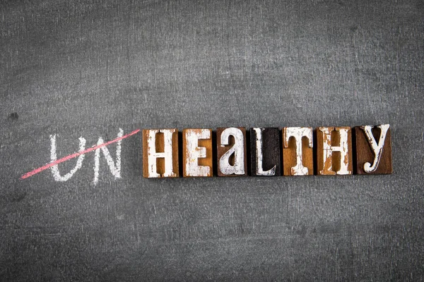 Unhealthy an Healthy concept. Wooden alphabet letters with text on a dark chalk board — Stock Photo, Image