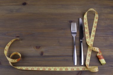 Bir çatal ve şerit metre ahşap arka plan üzerinde bıçak