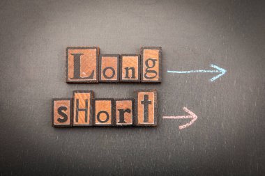 Long and Short with wooden block letters on chalkboard and arrows drawn in chalk. Symbol of difference, measurement, choice, perspective and strategic decision making.