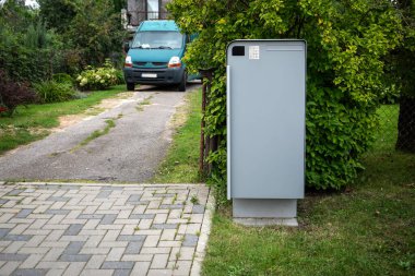 Güvenli paket teslimatları için garaj girişine yerleştirilmiş, yeşillik ve konut çevresi olan modern ev paketi..