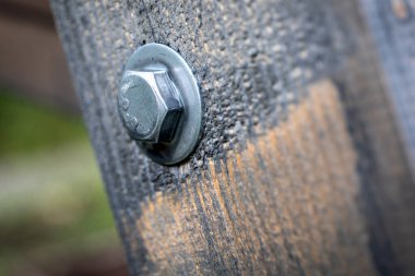 Metal cıvatanın detaylı makro görüntüsü ve ahşap bir yapının yıkanması, marangozluk, bağlanma ve inşaat gücünün vurgulanması..