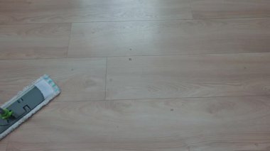 Düzenli temizlik sırasında ahşap zemini paspasla yıkayan kişi