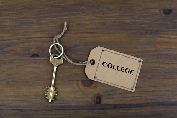 Nyckel och en kommentar på ett träbord med text - College — Stockfoto