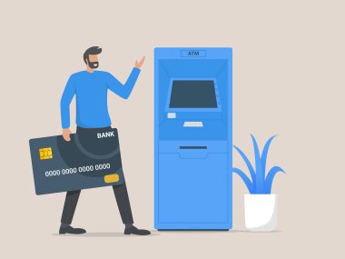 ATM makinesinin yanında duran ve kredi kartı tutan bir müşteri.