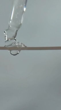 Güzellik serumu sıvısı yukarıdan bir serum pipetinin damlatarak sıvı kabarcıklar oluşturur.