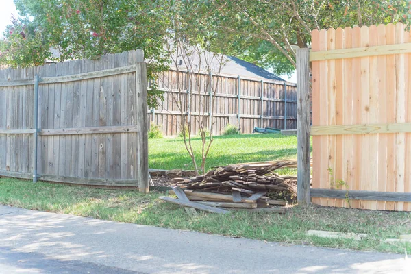 Concrete back alley with old fence near new lumber boards pickets at suburban residential house in Texas, USA