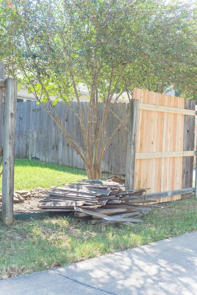Concrete back alley with old fence near new lumber boards pickets at suburban residential house in Texas, USA