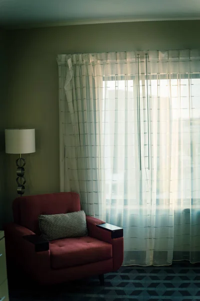 Típica habitación de hotel con sofá rojo y cortina de cierre cálida luz de la mañana retroiluminada — Foto de Stock